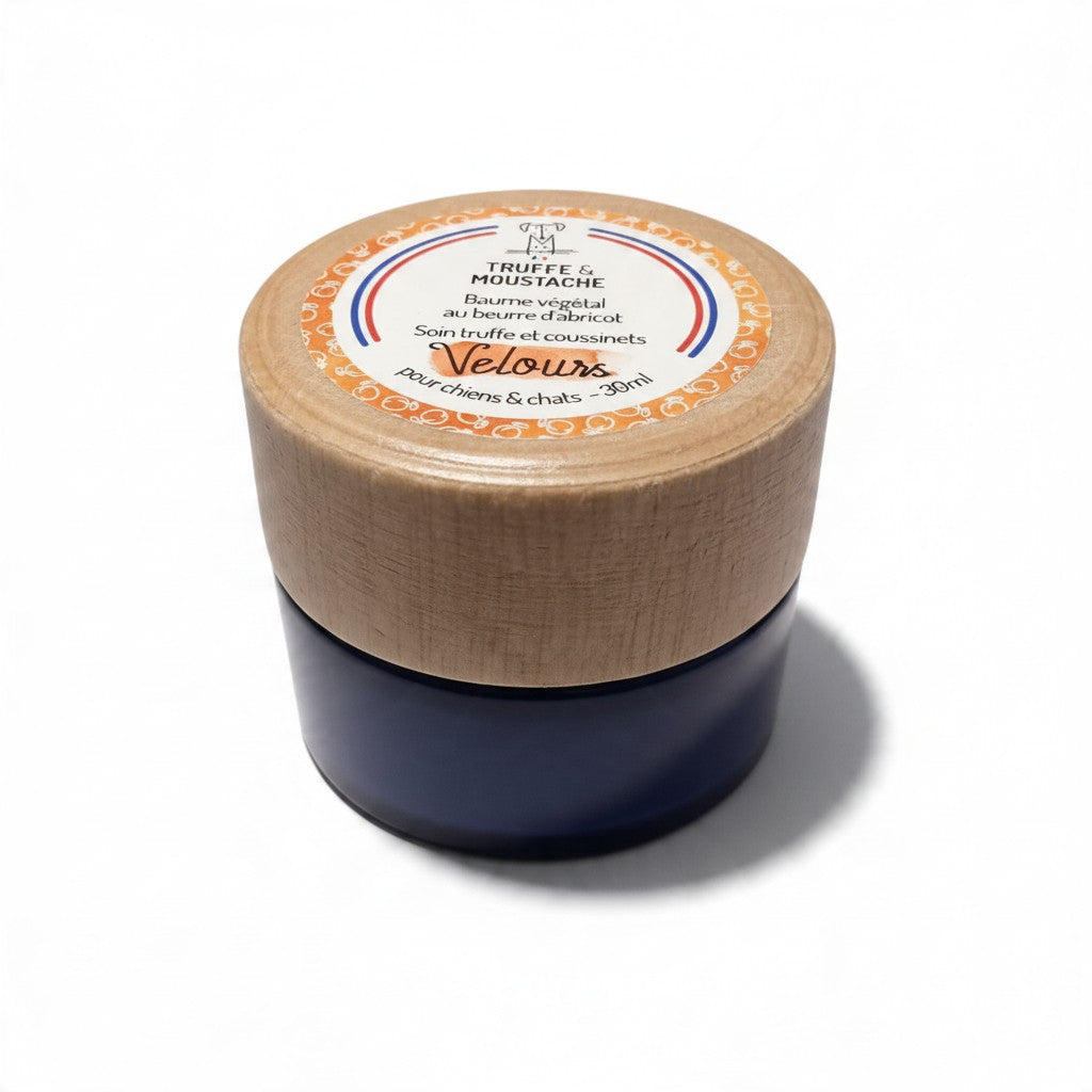 Pot de baume Velours de la marque Truffe & Moustache, en verre bleu avec couvercle en bois clair et étiquette ronde orange, blanche et tricolore, soin truffe et coussinets au beurre d’abricot pour chiens et chats, 30 ml