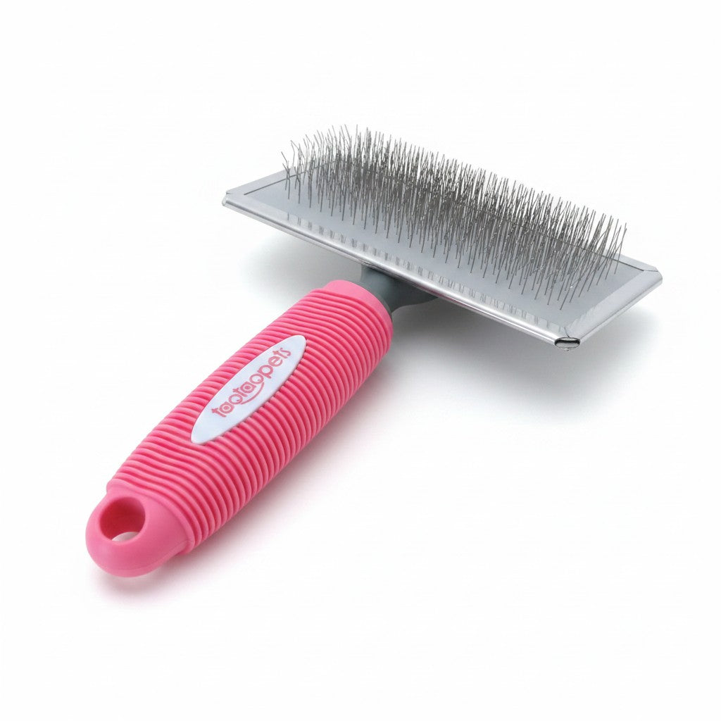 Brosse carde TAOTAOPETS rose pour chien avec large tête rectangulaire à fines tiges métalliques et manche ergonomique texturé.