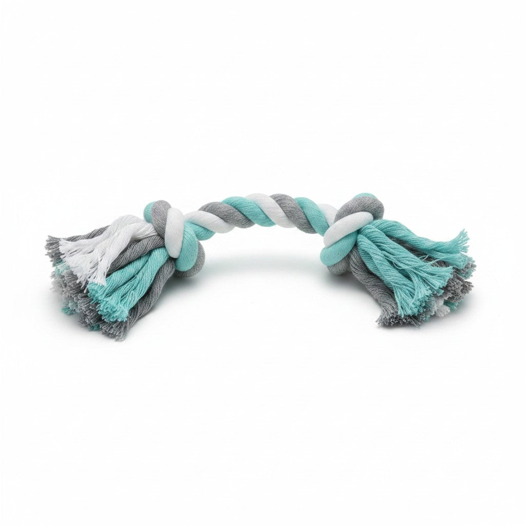 Un jouet en corde tressée pour chien, conçu avec des fils de coton blancs, gris et vert turquoise. La corde présente deux gros nœuds serrés à chaque extrémité, qui se terminent par des franges épaisses et ébouriffées. L'objet est légèrement courbé et photographié de face sur un fond blanc neutre.