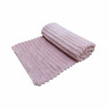 Couverture pour chien et chat en tissu ultra-doux de couleur rose poudré, présentée à moitié enroulée pour mettre en valeur ses rainures texturées sur fond blanc uni.