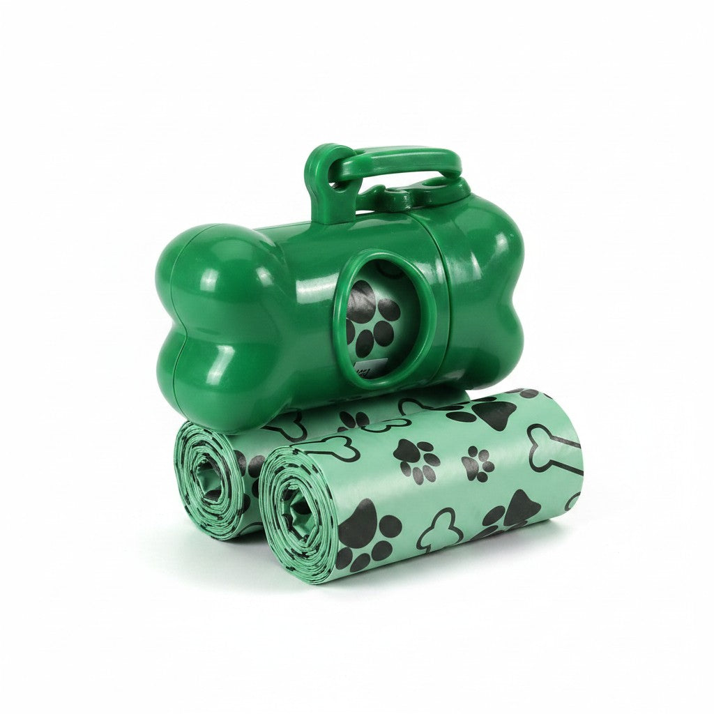 Distributeur de sacs à crottes vert en forme d'os avec mousqueton d'attache, posé sur deux rouleaux de sacs hygiéniques assortis à motifs de pattes et d'os de chien.