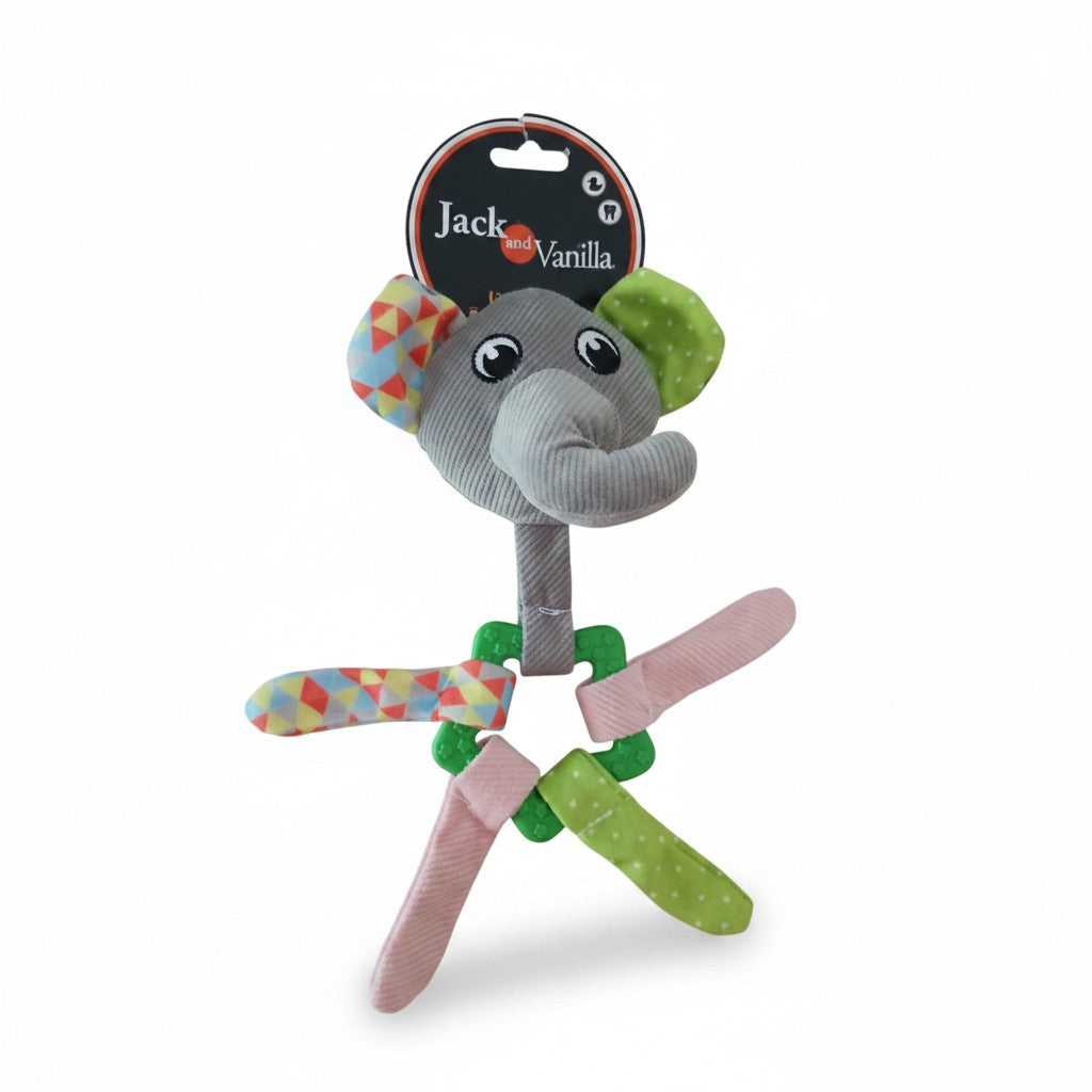 Jouet d'éveil pour chiot en forme d'éléphant de la marque Jack and Vanilla, présenté sur fond blanc. La tête de l'éléphant est en velours côtelé gris avec une oreille multicolore géométrique et une oreille verte à pois blancs. Le cou s'attache à un anneau de dentition dentelé en plastique vert, autour duquel sont nouées quatre lanières en tissu souple assorties (multicolore, rose, verte). L'étiquette ronde noire est visible au sommet.