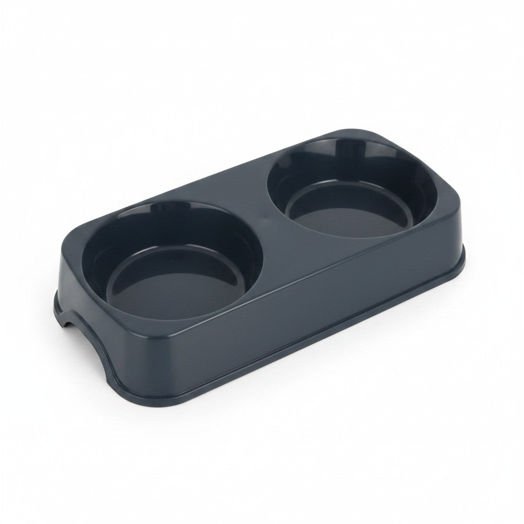 Une double gamelle rectangulaire pour animal de compagnie, conçue en plastique lisse brillant de couleur noire. Le bloc moulé comprend deux récipients circulaires de taille identique pour les aliments et l'eau. La base dispose d'une petite arche découpée sur le côté court pour soulever l'objet facilement. Le produit est photographié de trois-quarts sur fond blanc.