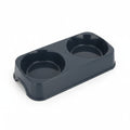 Une double gamelle rectangulaire pour animal de compagnie, conçue en plastique lisse brillant de couleur noire. Le bloc moulé comprend deux récipients circulaires de taille identique pour les aliments et l'eau. La base dispose d'une petite arche découpée sur le côté court pour soulever l'objet facilement. Le produit est photographié de trois-quarts sur fond blanc.