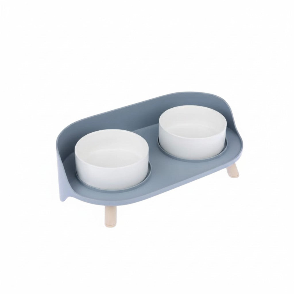 Gamelle double surélevée TIAKI pour petit chien avec deux bols blancs, support bleu gris à rebord et pieds couleur bois clair.