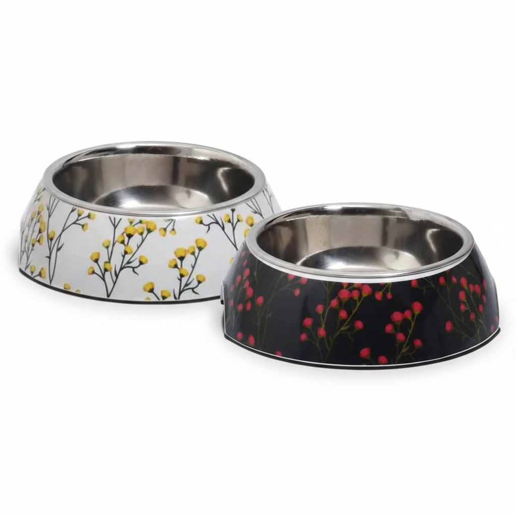 Présentation du duo de gamelles Fleur de la collection Croci. À gauche, le modèle blanc aux fleurs jaunes et à droite, le modèle noir aux fleurs roses, tous deux dotés de leur insert amovible en acier inoxydable.