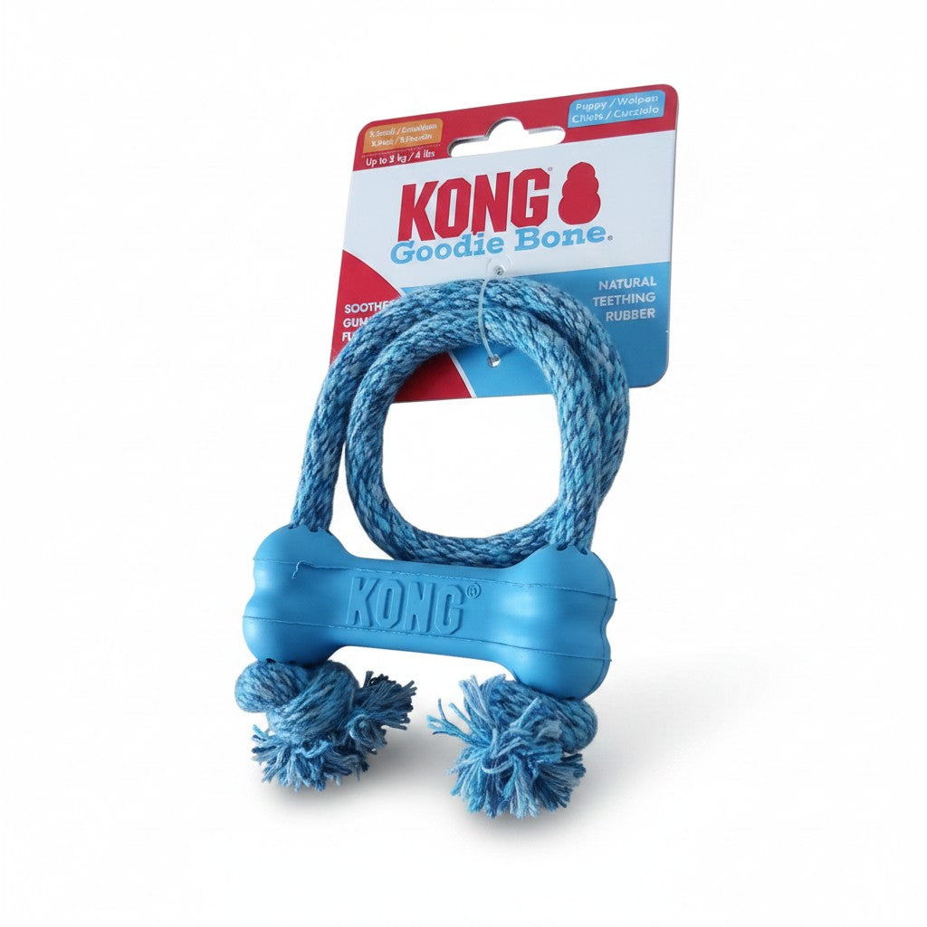 Jouet pour chiot KONG Puppy Goodie Bone avec corde, présenté dans son emballage d'origine sur fond blanc. Le jouet se compose d'un petit os en caoutchouc souple bleu clair, gravé du logo "KONG", traversé par une corde en coton bleu assorti formant une boucle supérieure et deux nœuds frangés à la base. Le carton d'emballage supérieur est bleu, rouge et blanc.