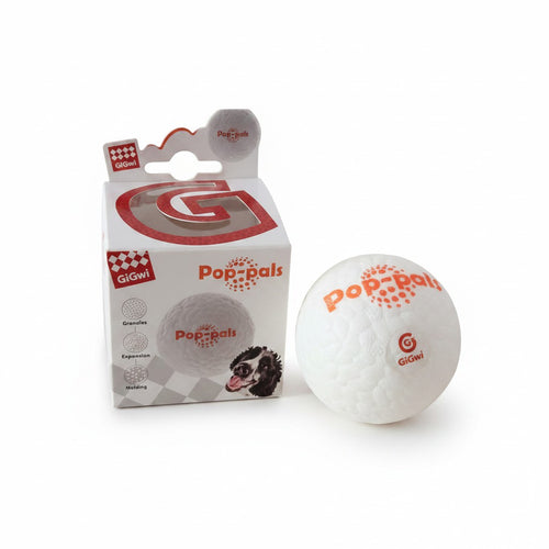 Balle pour chien blanche de la marque GiGwi, collection "Pop-pals", présentée à côté de sa boîte d'emballage d'origine sur fond blanc. La balle texturée affiche l'inscription orange "pop-pals" et le logo rond rouge "GiGwi". La boîte blanche et rouge présente une découpe en forme de G transparent sur le dessus, la photo d'un chien et des pictogrammes techniques.