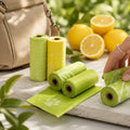 Rouleaux de sacs à déjections pour chien M-PETS verts et jaunes senteur citron, présentés près d’un sac et de citrons.