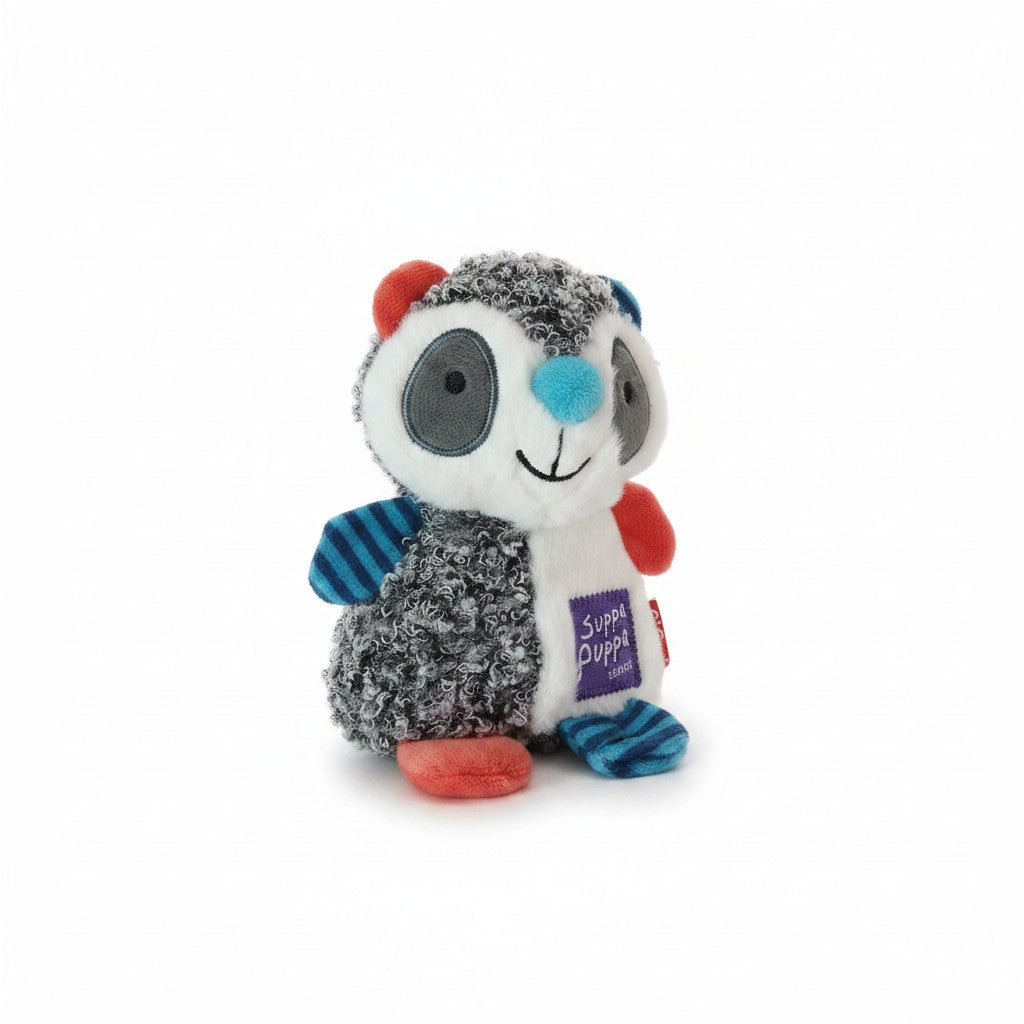 Un jouet en peluche pour chien de la marque GiGwi, issu de la collection "Suppa Puppa". Le personnage stylisé arbore un design patchwork asymétrique associant une fourrure bouclée grise et noire à du tissu blanc et des éléments colorés (oreilles et pattes rouge corail, bleu à rayures foncées). Son visage blanc présente un nez bleu turquoise en relief, des yeux ronds gris foncé et un sourire brodé. Un écusson violet "Suppa Puppa" est cousu sur son ventre.