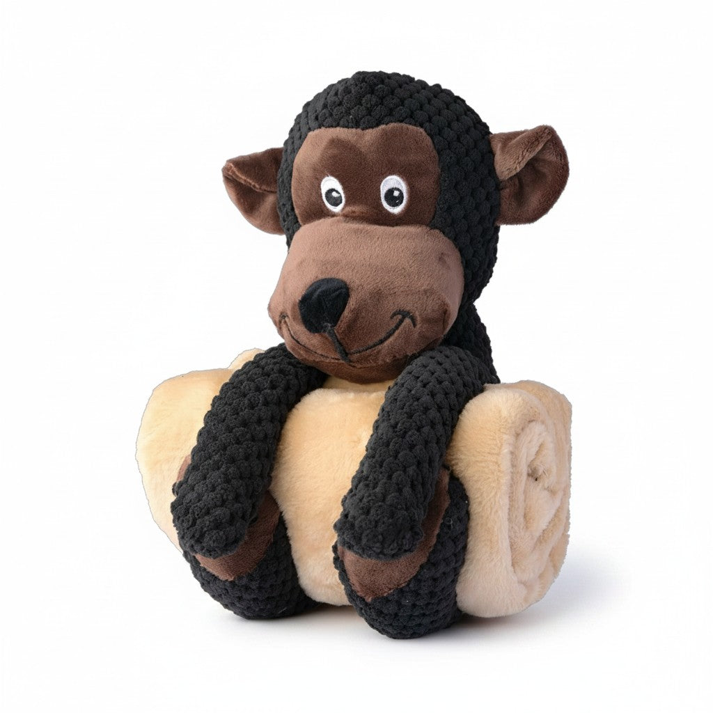 Une peluche pour chien en forme de singe marron foncé et beige, agrippée autour d'une couverture en polaire beige enroulée.